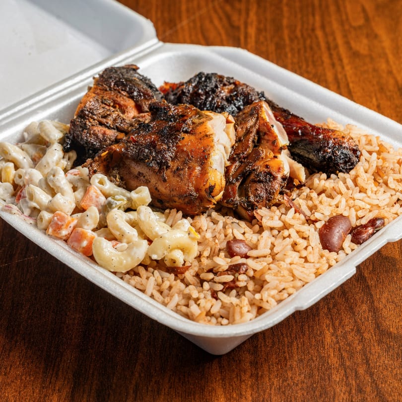 Jamrock Grill's jerk chicken with rice and peas, and macaroni salad in a takeout container.