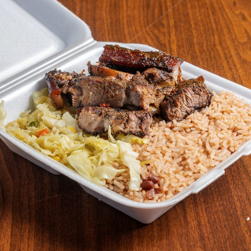 Jamrock Grill's Caribbean jerk pork with rice and peas, and steamed cabbage in a takeout container.
