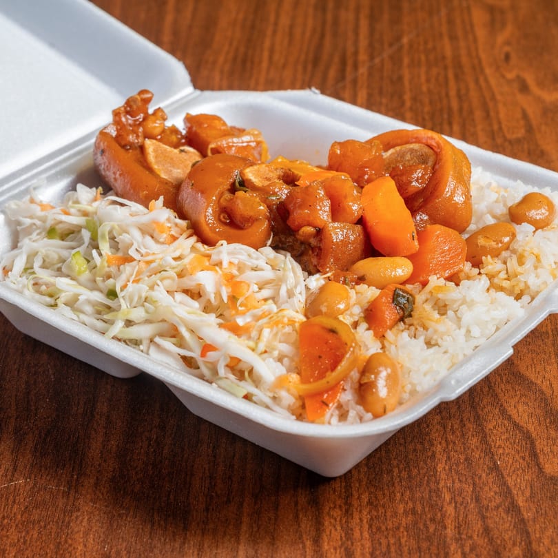 Jamrock Grill's Caribbean oxtail stew with rice and coleslaw in a white takeout container.